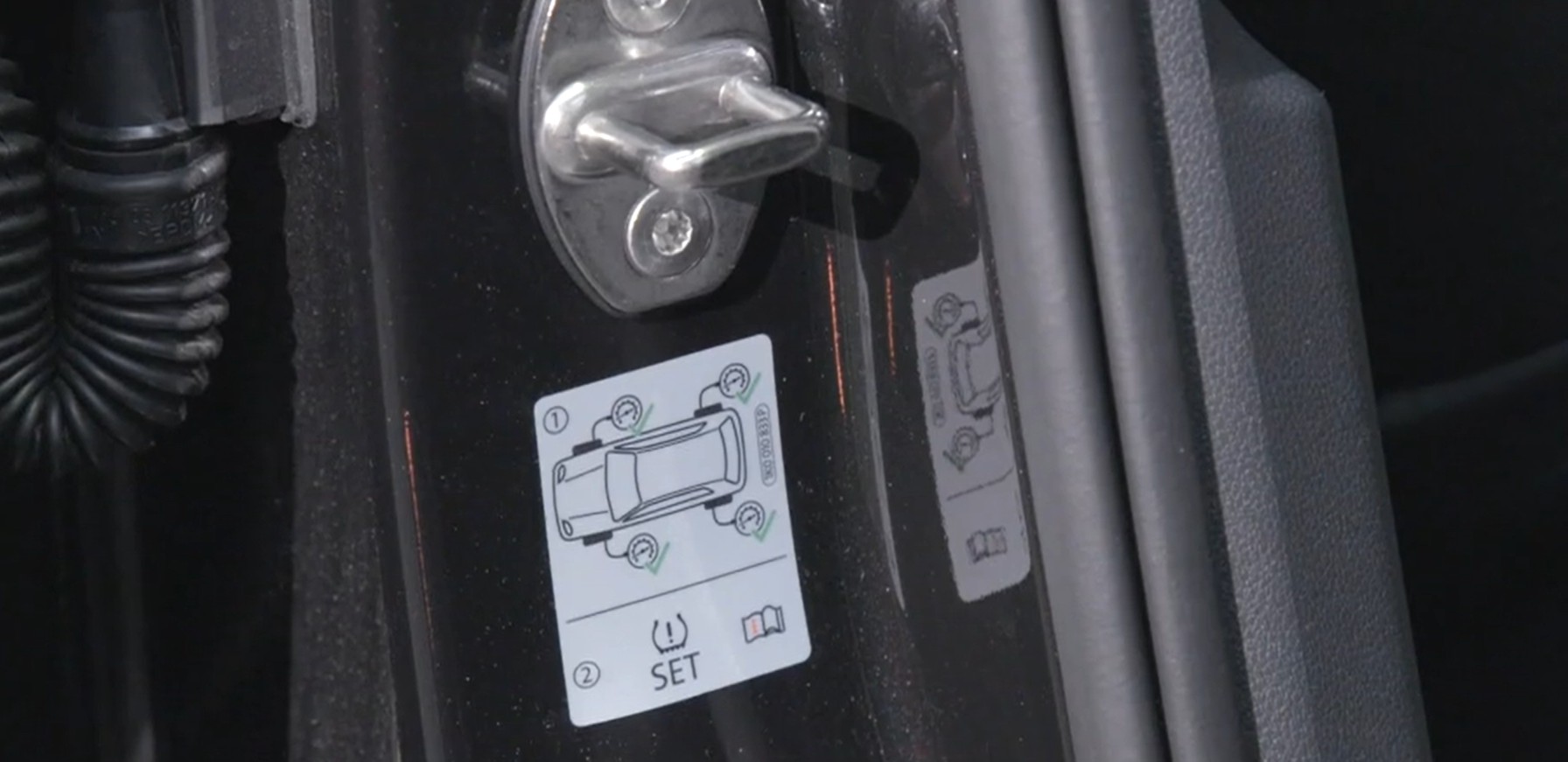 Tyre pressure reset instructions sticker on car door frame.