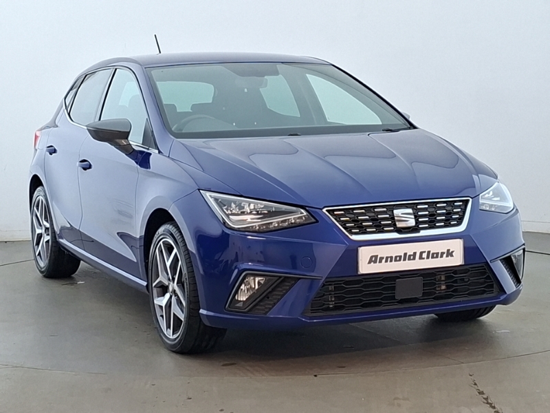 A blue SEAT Ibiza parked in front of a grey background