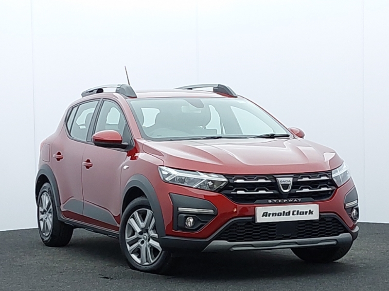 Red Dacia Sandero parked up in front of a grey background